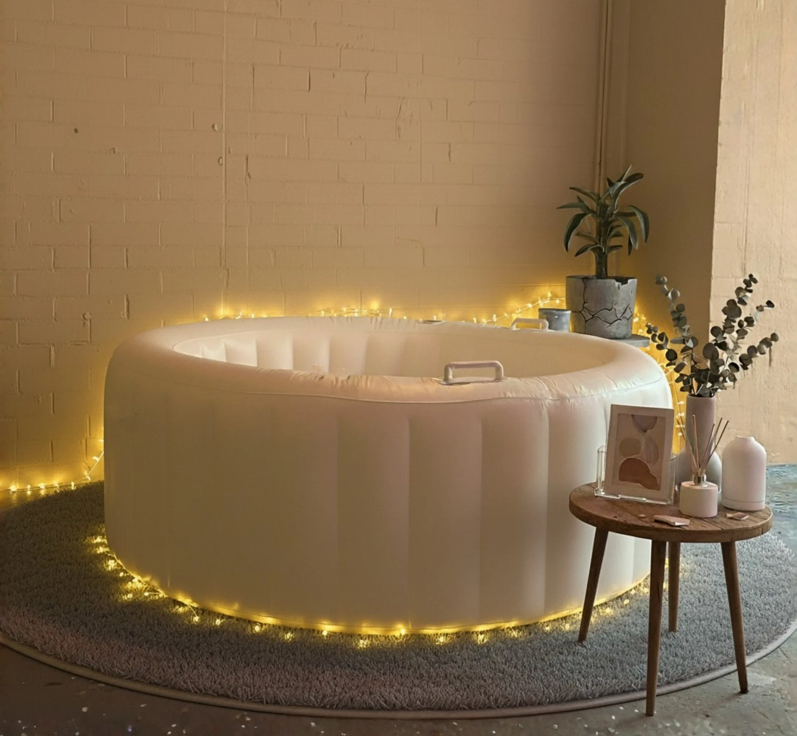 Lichtsnoer voor bevalbad - Een lichtslinger voor in het bevalbad Een volledig opgezet wit opblaasbaar bevalbad omringd met warme led-sfeerverlichting op een zacht rond tapijt.