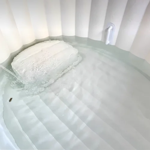 Binnenaanzicht van het opblaasbaar bevalbad gevuld met water, voorzien van een ingebouwd zitje, antislipbodem en stevige handgrepen.